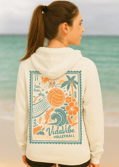 Woman wearing a hoodie with 'VidaVibe Volleyball' design on a beach